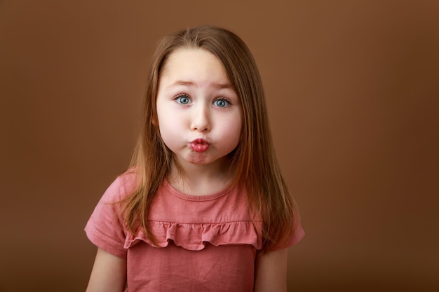 Foto niña divertida estirando sus labios en un beso