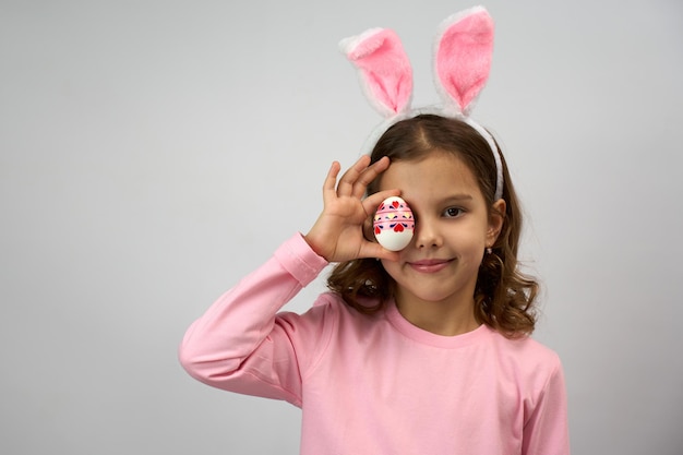 Una niña divertida y feliz con huevos de Pascua y orejas de conejo.