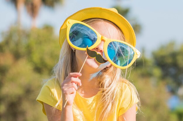 Niña divertida con máscara de papel. Cumpleaños de niños, diversión de verano.