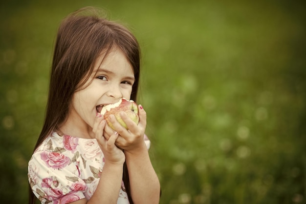 Niña divertida mordiendo manzana