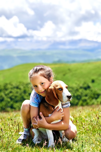 Niña divertida con un perro en las montañas.