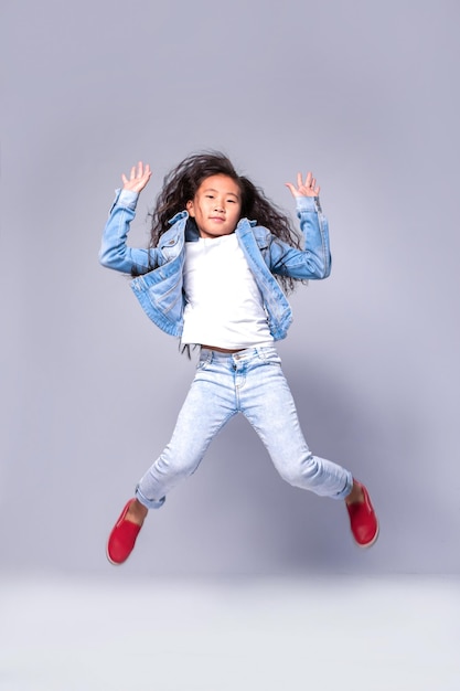 Niña divertida saltando sobre un fondo claro en el estudio