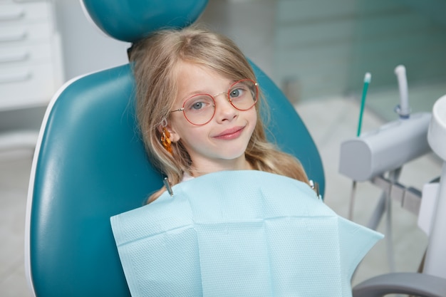 Niña divertida sentada en un sillón dental