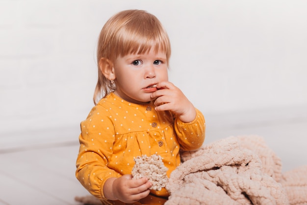 Niña divertida se sienta y sostiene un pan de cereal en su mano