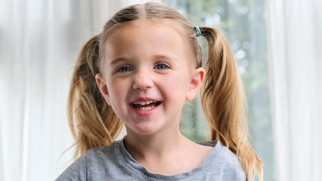 Niña divertida sonriendo mirando a la cámara en casa