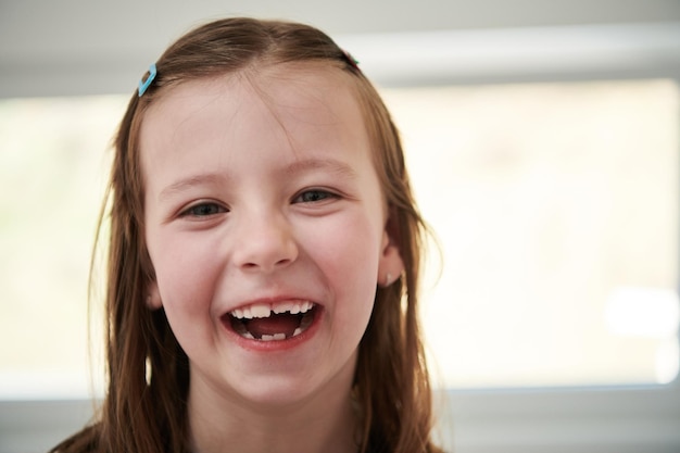 Niña divertida sin sonrisas de dientes que muestra la brecha de cerca