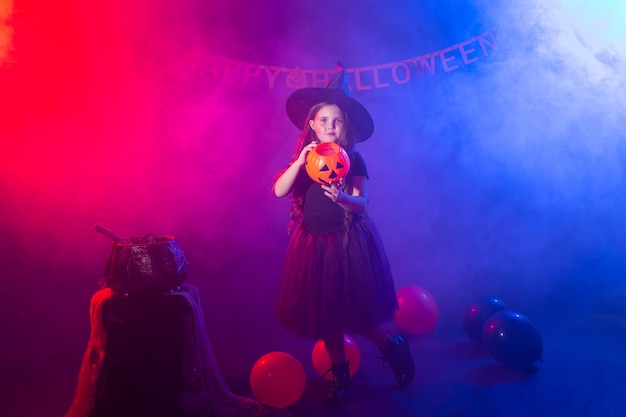 Niña divertida en traje de bruja para Halloween con calabaza Jack.