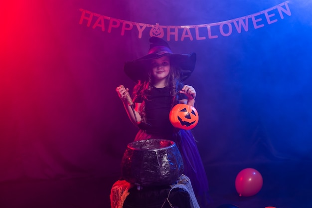 Niña divertida en traje de bruja para Halloween con calabaza Jack.