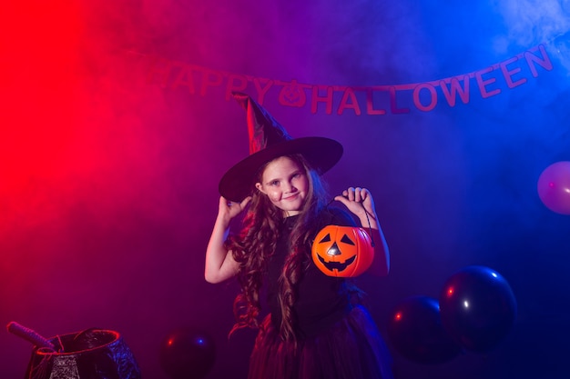 Niña divertida en traje de bruja para Halloween con calabaza Jack.