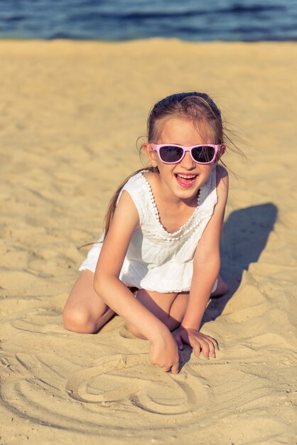 La niña divertida en vidrios de sol está mirando la cámara.