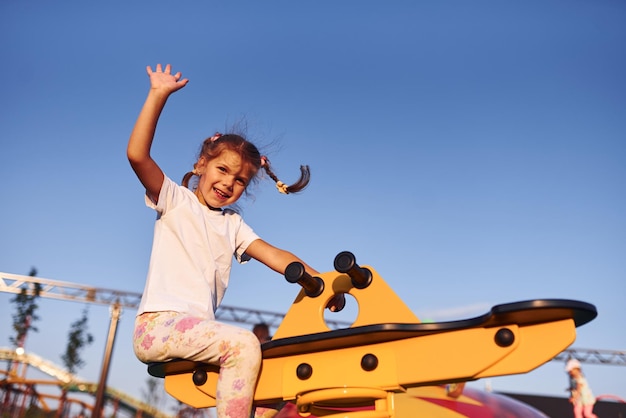 La niña se divierte en el parque de diversiones para niños durante el día