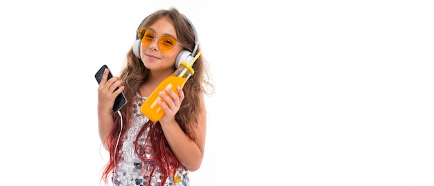 Niña divirtiéndose escuchando música y bebiendo jugo