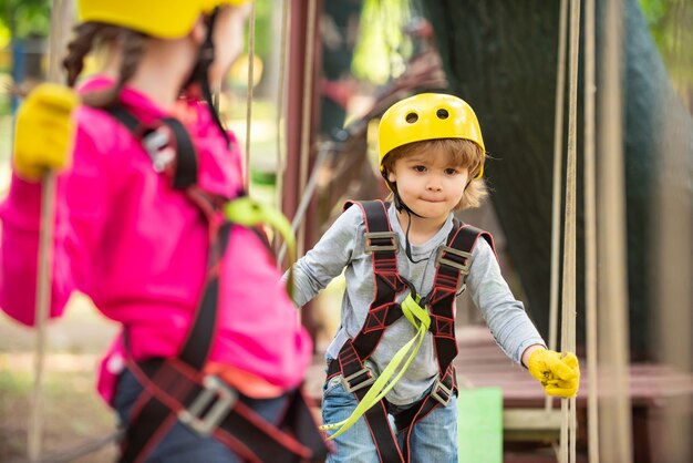 Niña divirtiéndose en el parque de aventuras niño trepando árboles en el parque niña linda en escalada segura ...