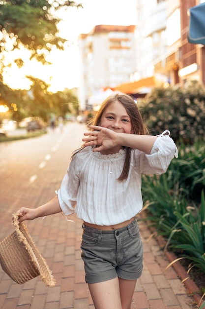 Niña divirtiéndose en la puesta de sol de la ciudad Hermosa niña con sombrero de paja