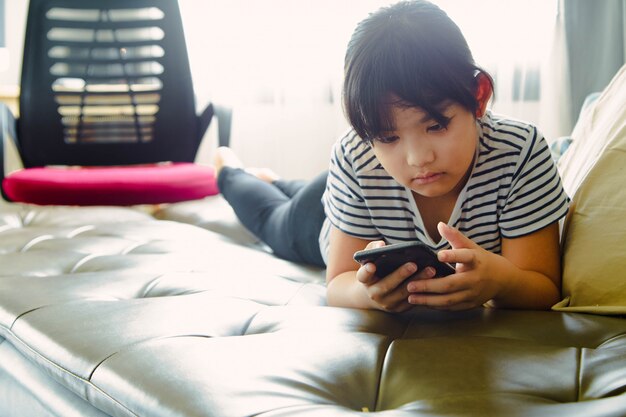 Niña divirtiéndose con el uso de teléfonos inteligentes en casa