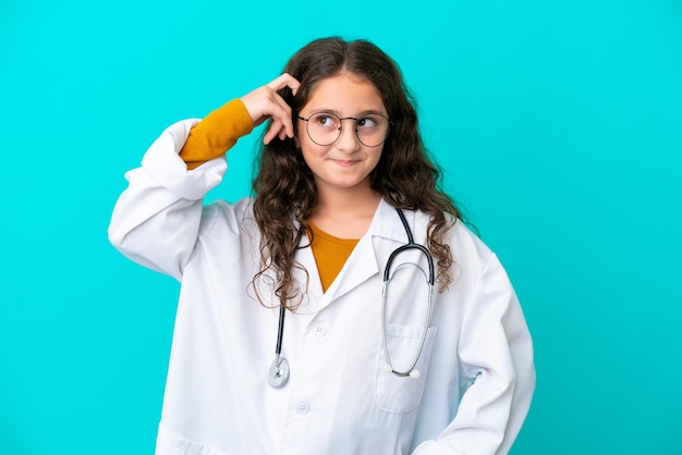 Niña doctora aislada de fondo azul que tiene dudas y con expresión facial confusa