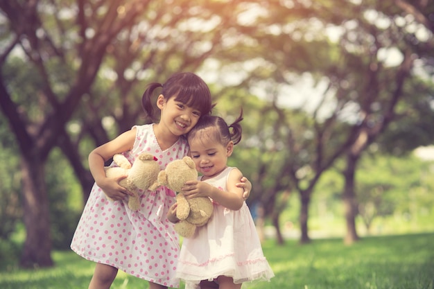 Niña dos abrazos en el bosque con peluche baer