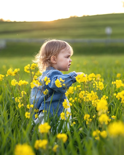 Una niña de dos años camina en la hierba alta de un prado florido