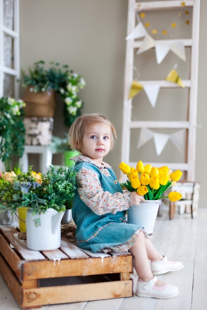 Niña de dos años con ramo de tulipanes amarillos