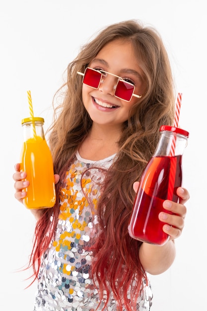 Niña con dos cócteles de colores sonríe a la cámara