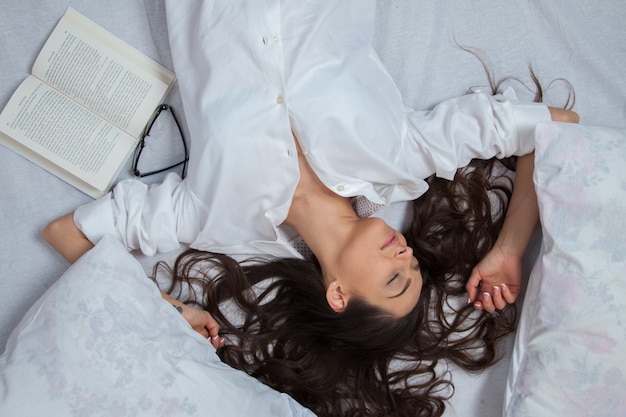 Niña duerme en una cama blanca en casa