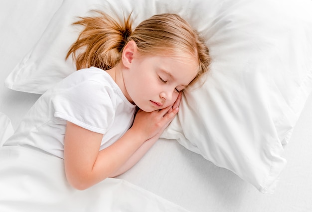 Niña durmiendo en la cama blanca