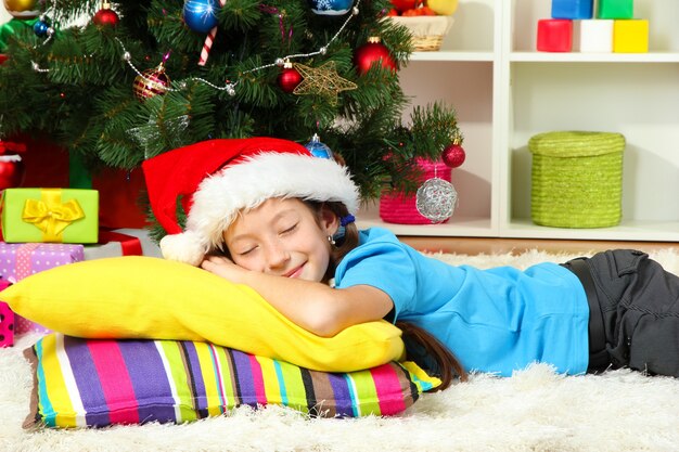 Niña durmiendo cerca del árbol de navidad