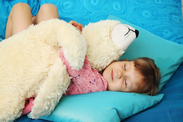 Niña durmiendo con oso de peluche