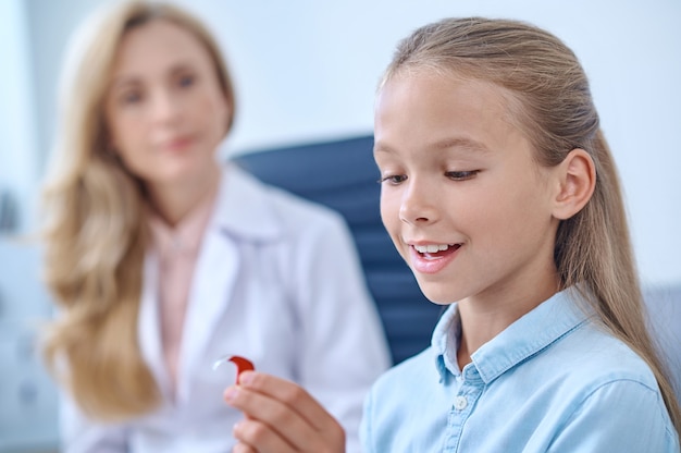 Niña en edad escolar feliz admirando el audífono