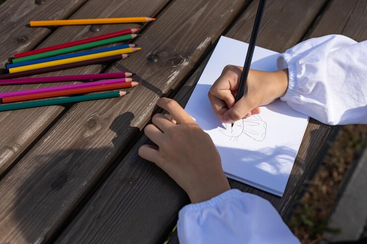 Foto niña en edad preescolar dibujando con lápices de colores al aire libre desarrollo de la creatividad
