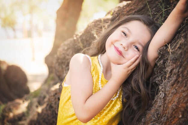 Niña en edad preescolar posando en un árbol en el bosque tema del día de los niños día internacional del árbol