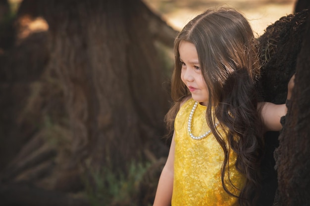 Niña en edad preescolar posando en un árbol en el bosque tema del día de los niños día internacional del árbol