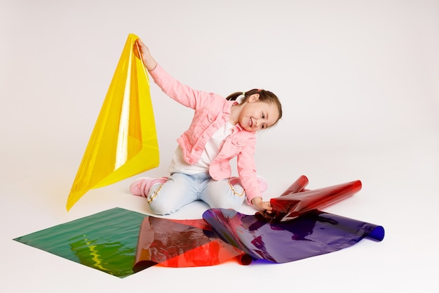 Niña en edad preescolar que aprende colores y sus combinaciones utilizando láminas de colores, desarrollo temprano y concepto de aprendizaje.