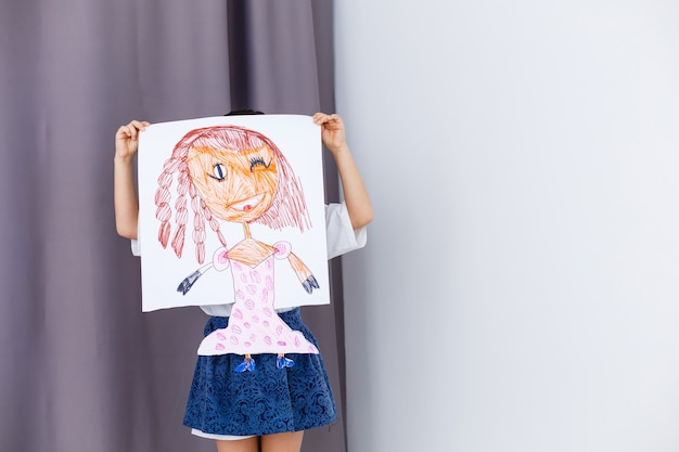 Niña en edad preescolar sosteniendo su imagen de retrato