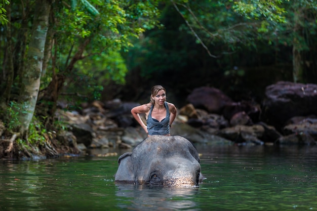 La niña con el elefante en el agua.