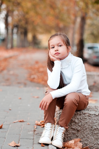 Niña elegante con ropa informal posando al aire libre