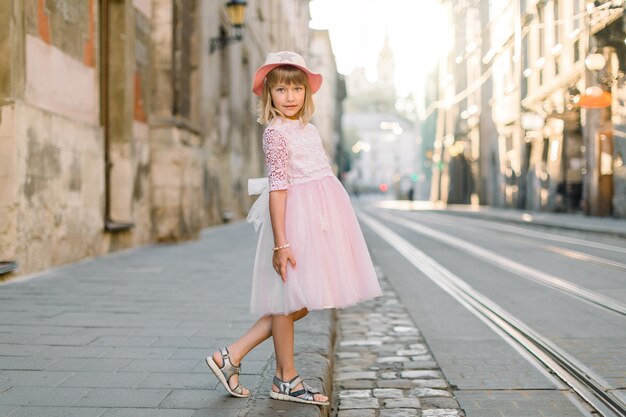 Niña elegante con sombrero y vestido rosa