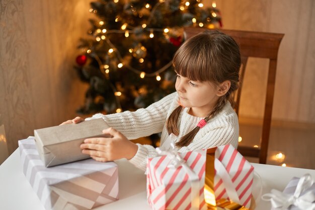 Niña, embalaje, regalos de navidad, sentar mesa