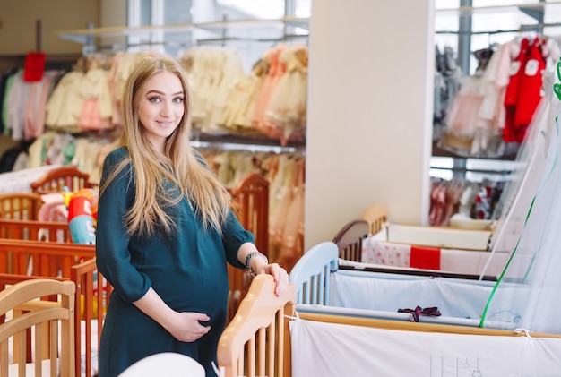 Niña embarazada elige una cuna en la tienda.