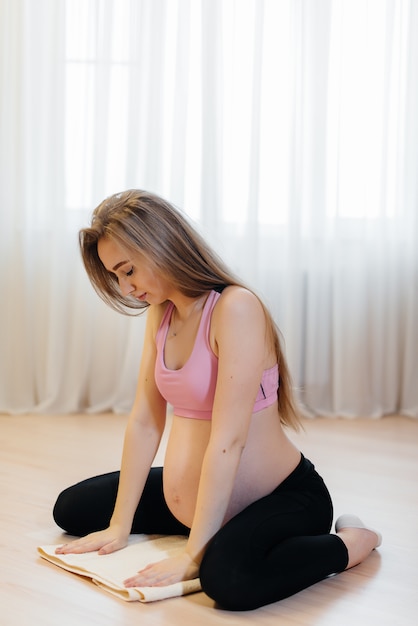 Una niña embarazada hace yoga en casa. Salud