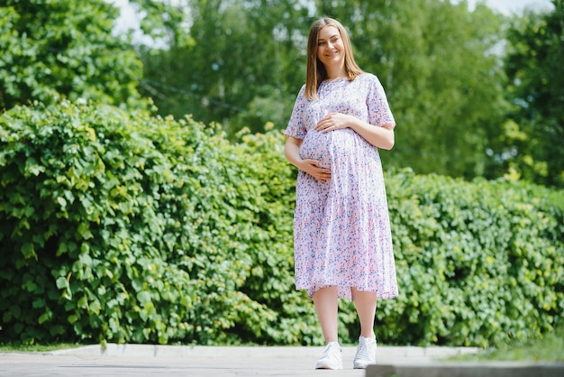 La niña embarazada a pie en el parque de la ciudad