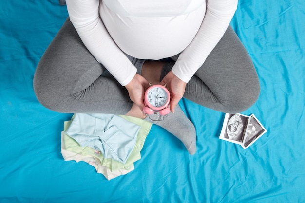 Niña embarazada ropa para niños inyecciones de ultrasonido reloj en la mano El concepto de esperar el nacimiento del niño