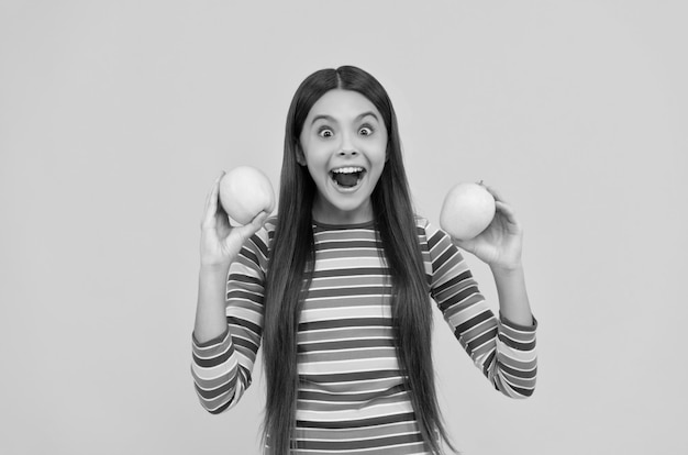 Niña emocionada sostener manzanas para dientes sanos fondo amarillo dieta dental