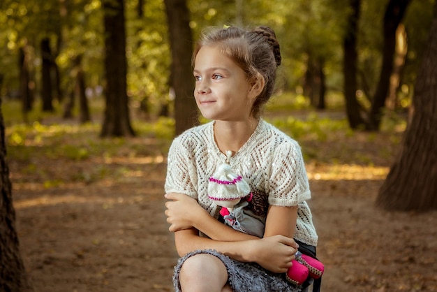 Niña encantadora en el bosque con muñeca