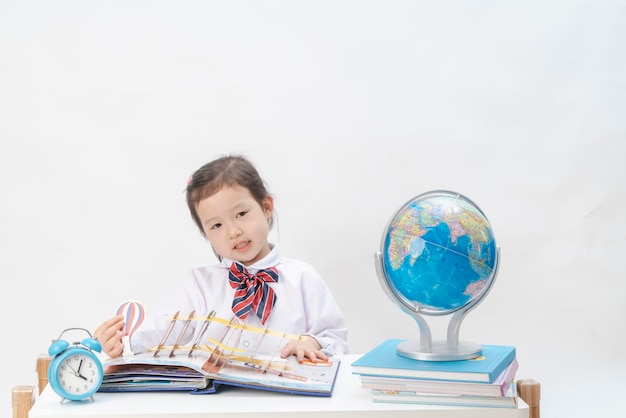 La niña encantadora está aprendiendo geografía en su escritorio.