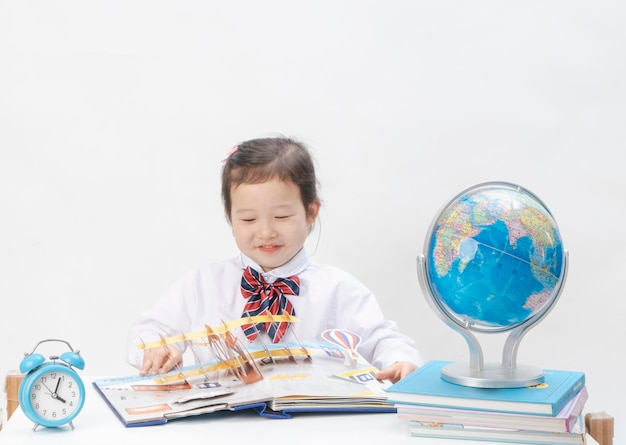 La niña encantadora está aprendiendo geografía en su escritorio.