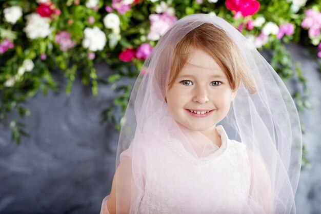 La niña encantadora juega contra las flores. Retrato de la niña bonita sonriente