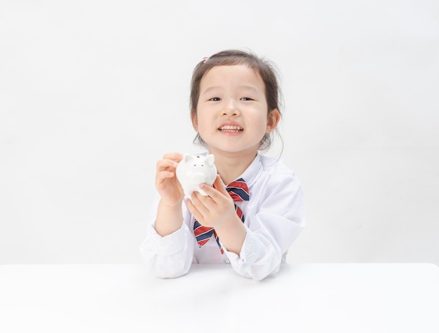 La niña encantadora tiene una alcancía en la mano.