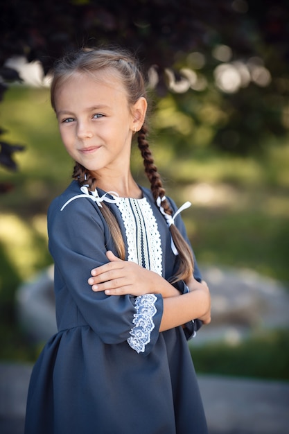 Niña encantadora con un vestido retro caminando por la ciudad en un día soleado de verano. Niña usa uniforme escolar.