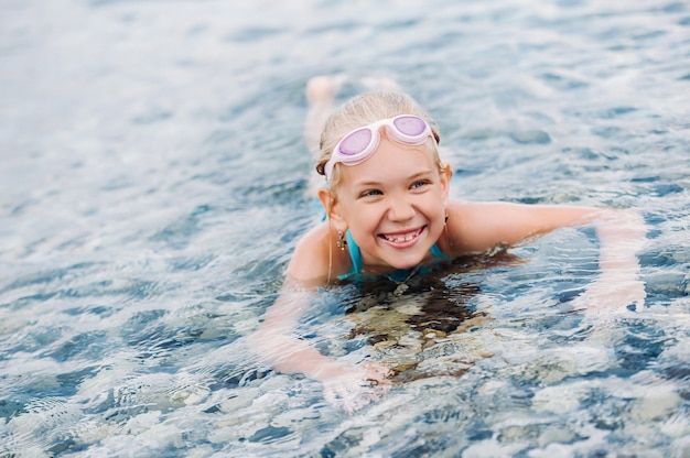 Una niña encantadora yace en el mar y sonríe. Una niña yace en el agua riendo. Turquía.